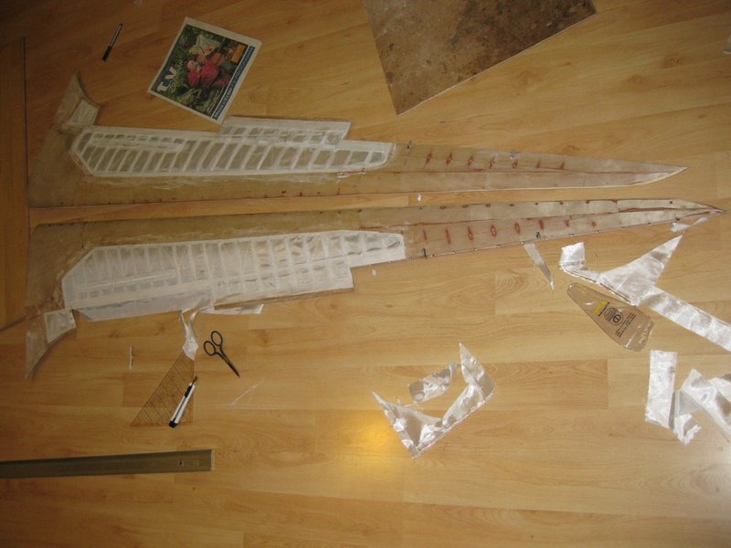 Bespannt man nur Teile eines Flügels, dann ist besser das Koverall grob zuzuschneiden und festzukleben und erst nach dem trocknen der ersten Spannlackschicht die genaue Form mit einem scharfen Cutter zuzuschneiden. Das zähe Gewebe läßt sich mit etwas getrocknetem Spannlack darin viel besser zuschneiden und der Gewebeüberstand läßt sich noch problemlos abziehen.