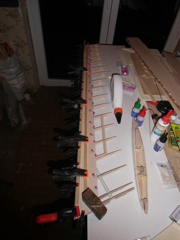 Aufbringen der Beplankung mit der Leistenspannmethode. Mit langen Leimzwingen bracht man auch keine Nadeln. Die Klemmleisten werden an den beiden Holmen und dem Nasenleistenbereich an angesetzt, die Leimzwingen immer an den Rippen gesetzt.